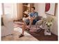 Homme en chemise bleue et short assis dans un fauteuil de salon.
