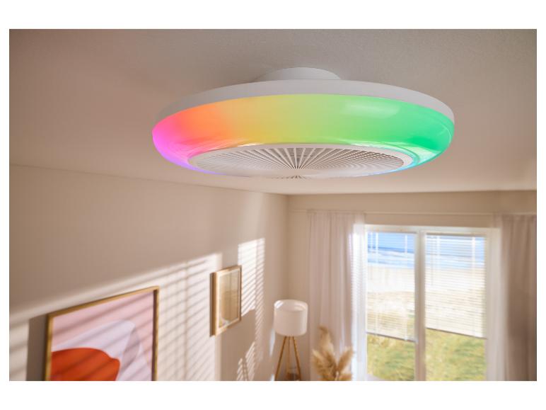 Ventilateur de plafond avec lumière LED colorée dans une pièce lumineuse avec stores