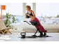 Femme s'entraînant sur un banc à lombaires avec un kettlebell, plante et fenêtre en arrière-plan.