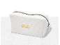 Trousse de toilette blanche avec fermeture éclair noire et initiales 'DL' brodées en jaune.