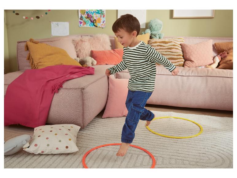 Un jeune enfant joue avec des cerceaux sur un tapis moelleux.