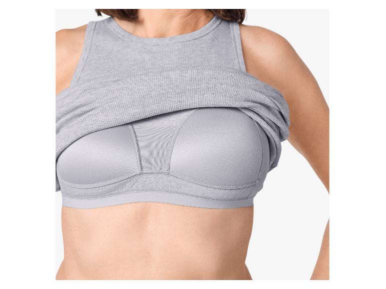 Femme portant un débardeur gris côtelé remonté pour révéler un soutien-gorge de sport gris.