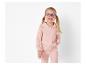 Une jeune fille avec un sweat à capuche rose et un pantalon.