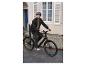 Un homme roule à vélo électrique noir en ville.