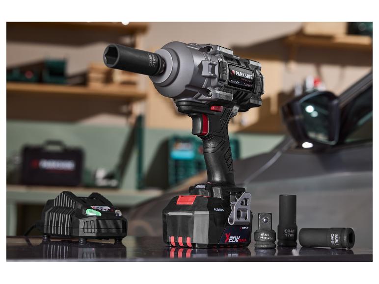 Clé à chocs avec batterie, chargeur et douilles, avec une voiture en arrière-plan.