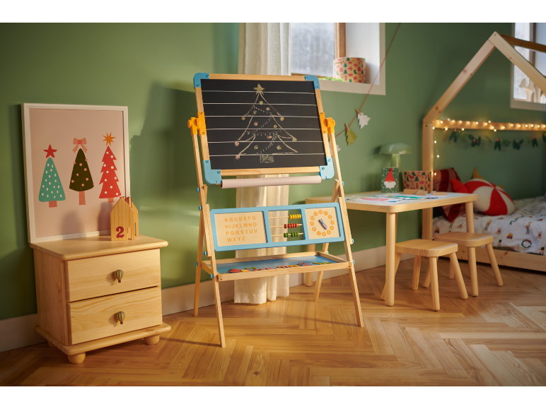 Chambre d'enfant avec chevalet en bois, petite table avec tabourets et lit, décorée pour Noël.