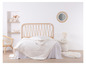 Un lit avec une tête de lit en rotin, une couette blanche et un tapis blanc.