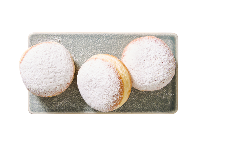 Trois beignets au sucre glace sur une assiette rectangulaire grise.