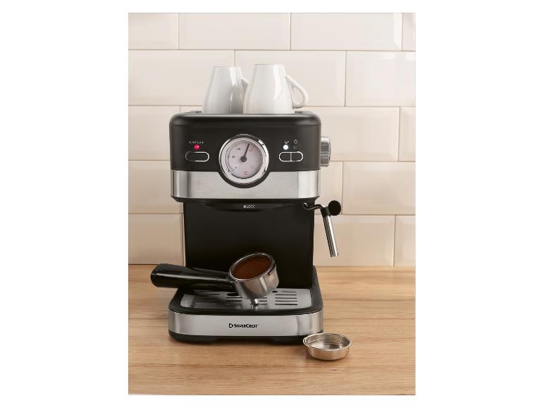 Machine à expresso avec deux tasses et porte-filtre avec café sur un comptoir en bois.