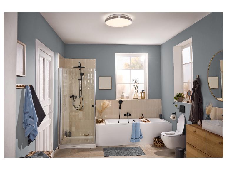 Salle de bain moderne avec douche, baignoire, toilettes et meuble-lavabo en bois, murs bleu-gris.