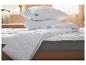Couette et oreillers blancs sur un lit.