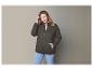 Une femme porte une veste vert foncé zippée et un jean bleu.