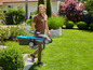 Un homme marche avec une tondeuse à gazon bleue dans son jardin.