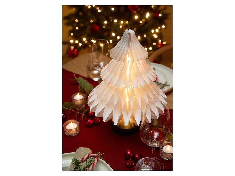 Table de Noël décorée d'un sapin en papier illuminé, de bougies et d'ornements rouges.