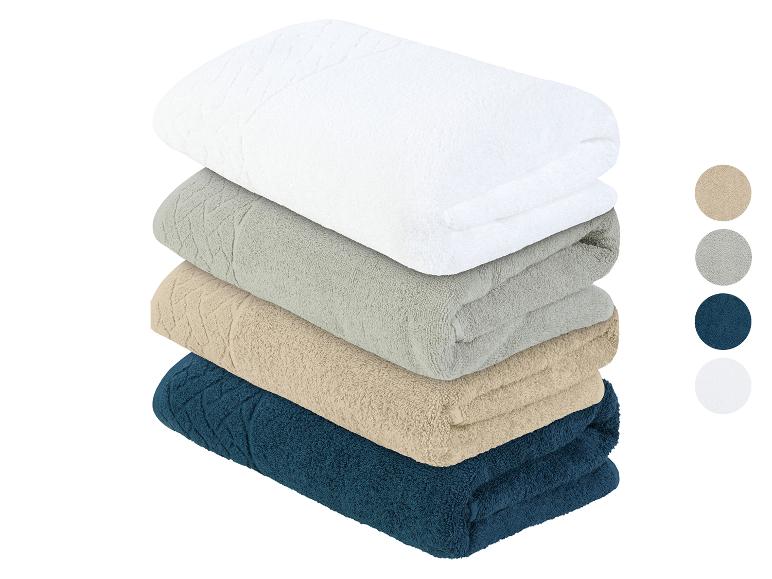Quatre serviettes de bain en blanc, gris, beige et bleu foncé.