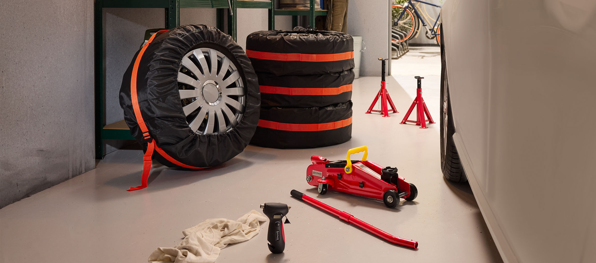 Pneus de voiture avec housses, cric et chandelles dans un garage.