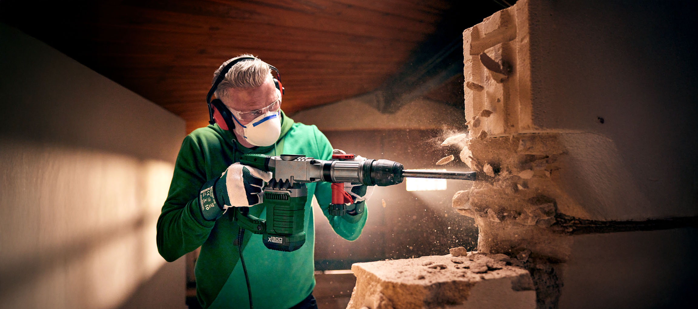 Un homme utilise un marteau-piqueur Bosch X1300 pour démolir un mur en blocs de béton.