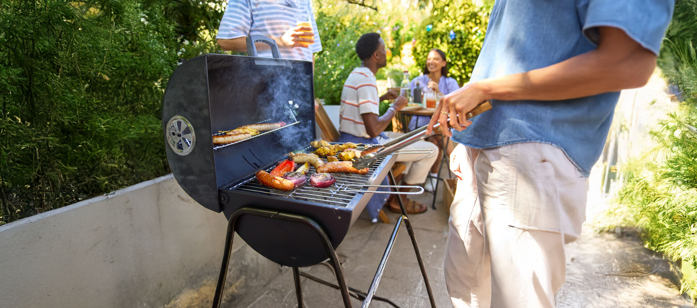Un barbecue au charbon de bois avec des saucisses et des légumes grillés.