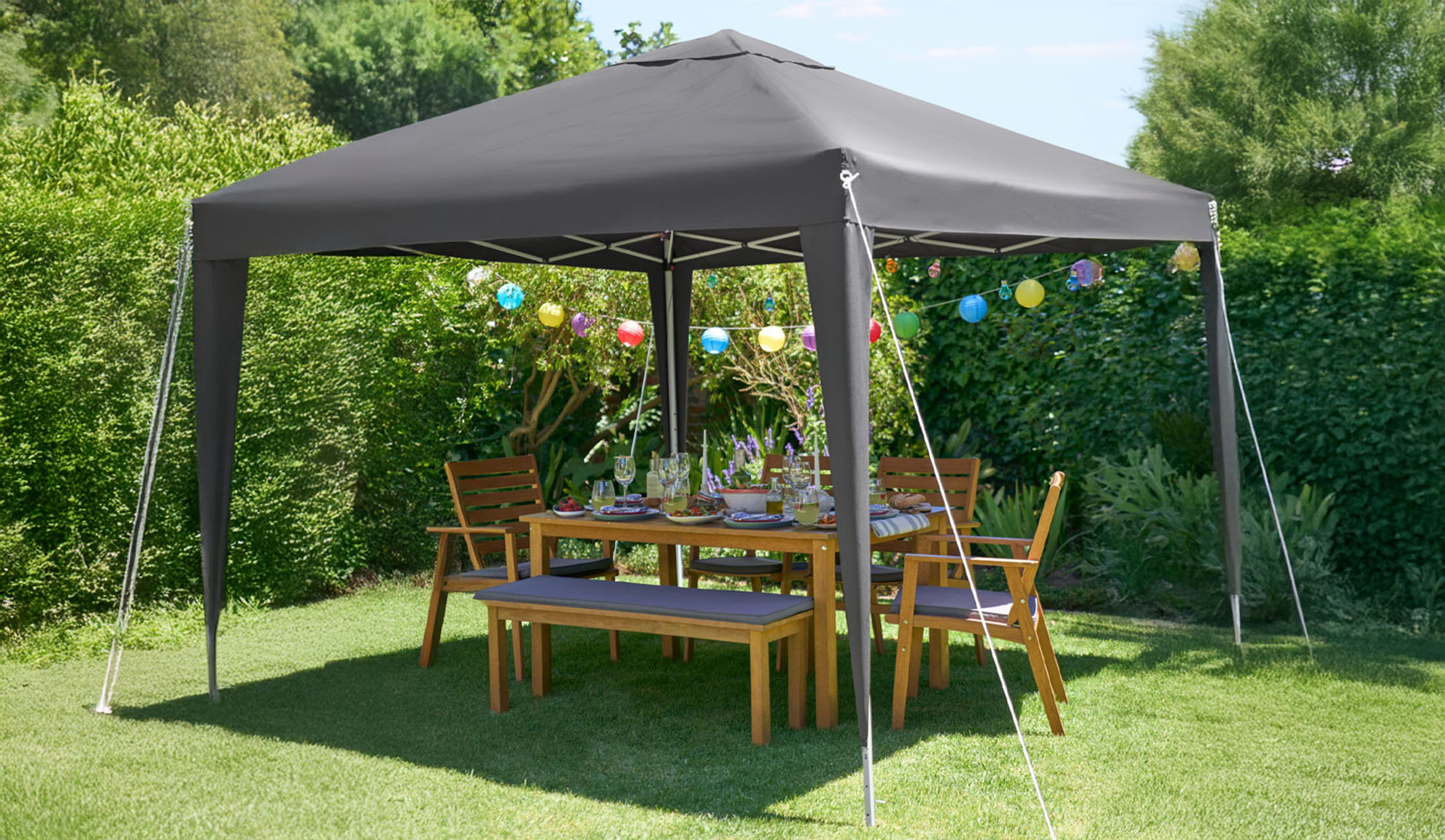 Gazebo de jardin gris foncé avec table et chaises en bois.