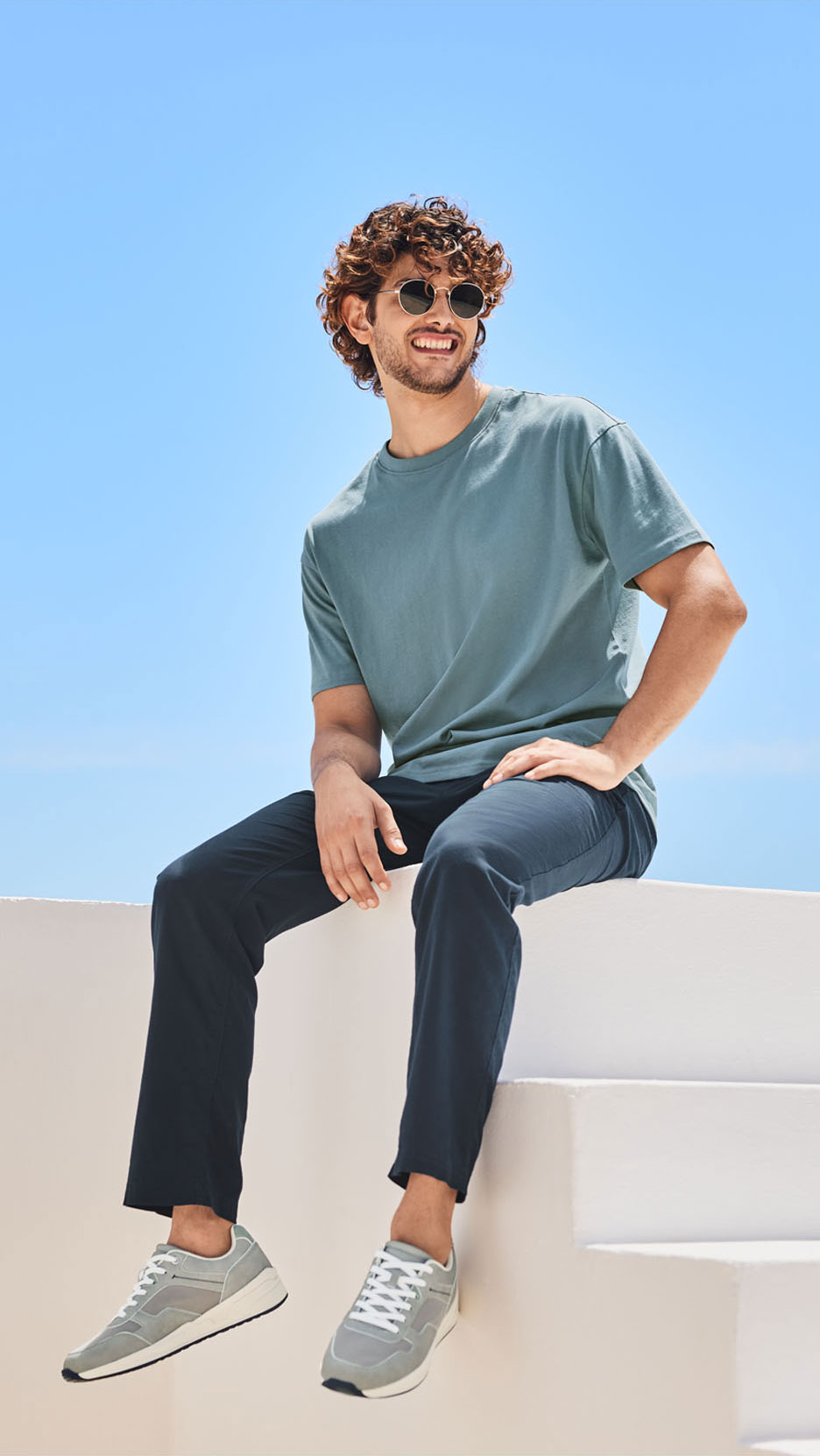 Homme en t-shirt vert clair, pantalon bleu marine et baskets grises.