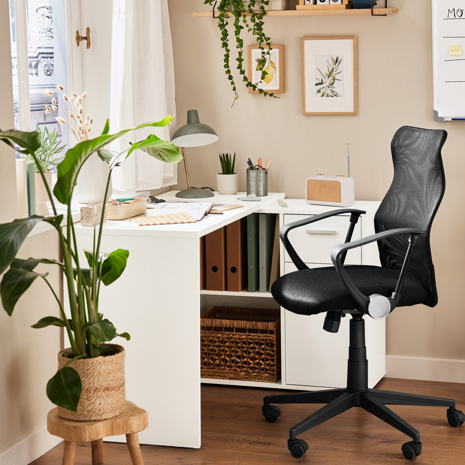 Un bureau d'angle blanc avec une chaise de bureau noire et des plantes vertes.