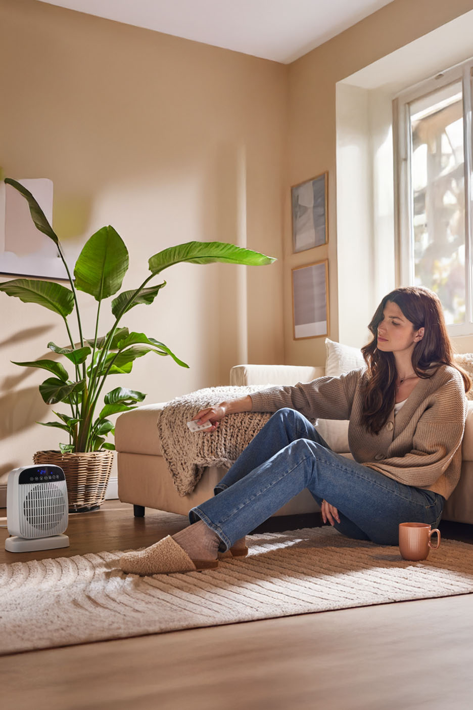 Une femme assise sur un canapé utilisant un chauffage portable.