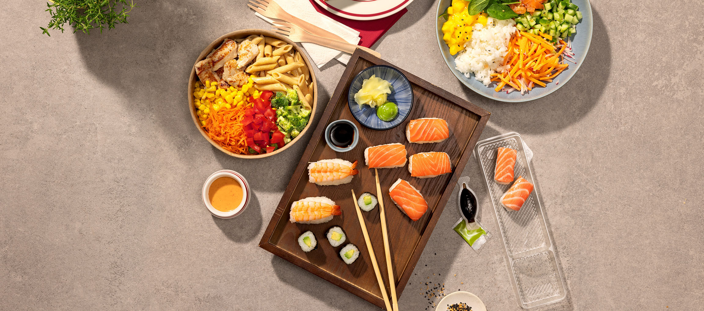 Plats variés : bol de pâtes et poulet, sushis et un poke bowl sur une table.