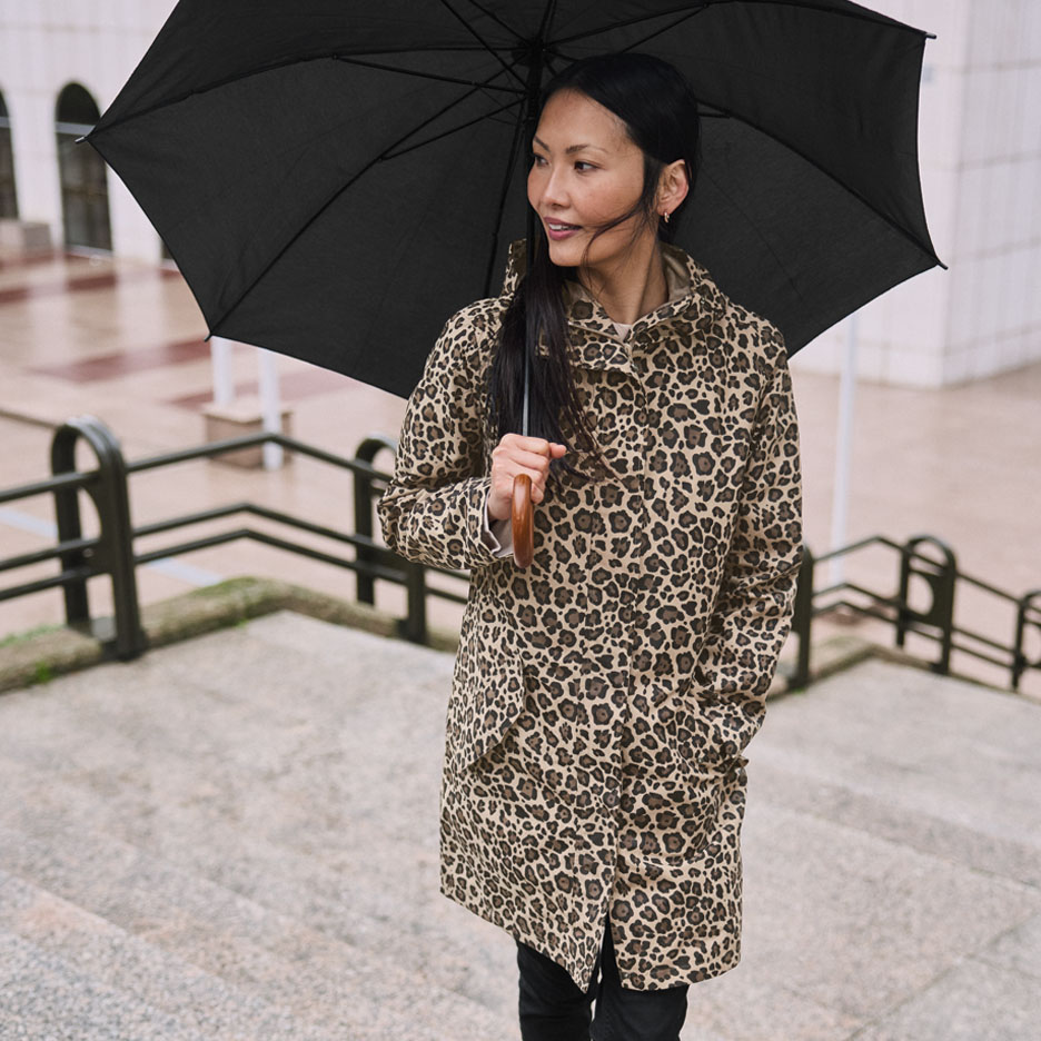 Femme en manteau léopard avec parapluie dans les escaliers.
