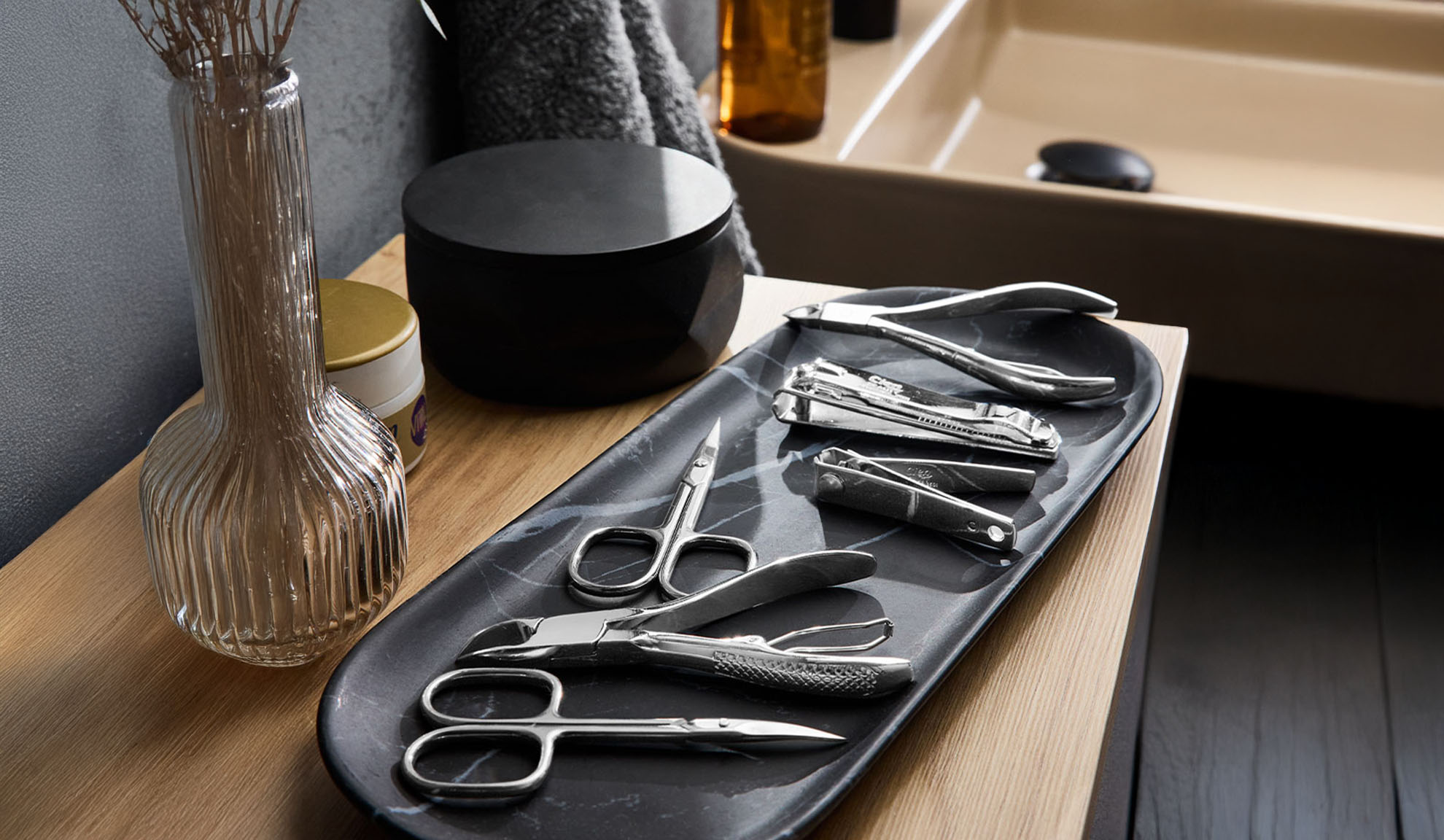 Outils de manucure et pédicure sur un plateau près d'un lavabo.