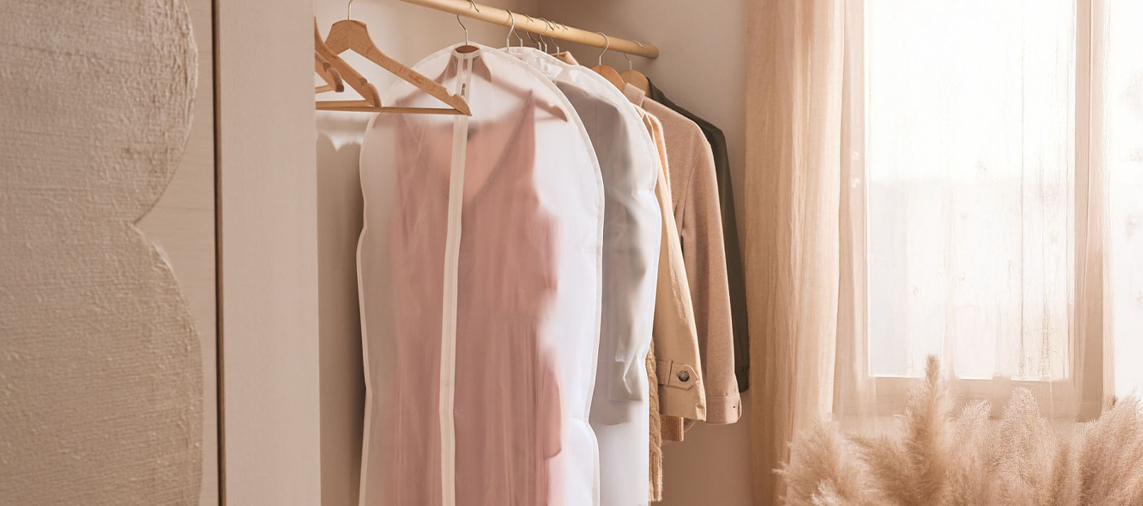 Housses de vêtements et vêtements sur cintres dans un placard près d'une fenêtre.