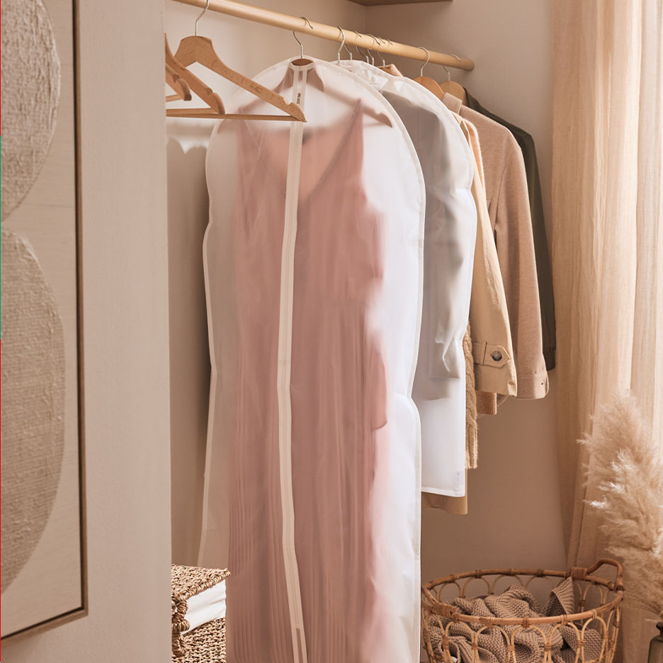 Vêtements sur cintres, dont une robe rose dans une housse de protection, dans un placard.
