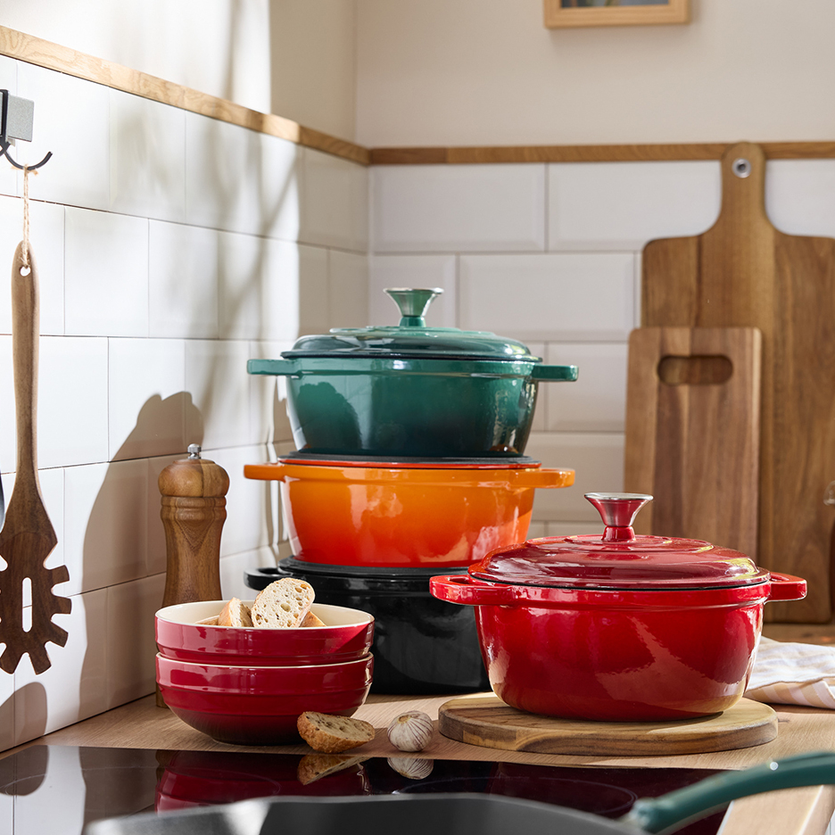 Une collection de cocottes en fonte émaillée colorées, de bols et d'ustensiles de cuisine.