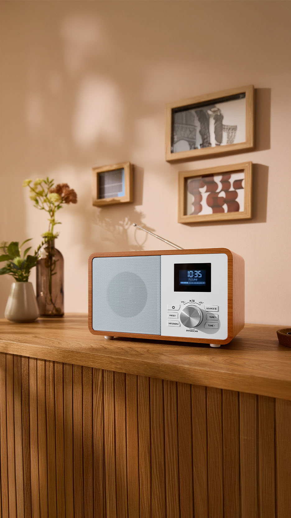 Radio en bois sur un meuble en bois avec des vases et des cadres.