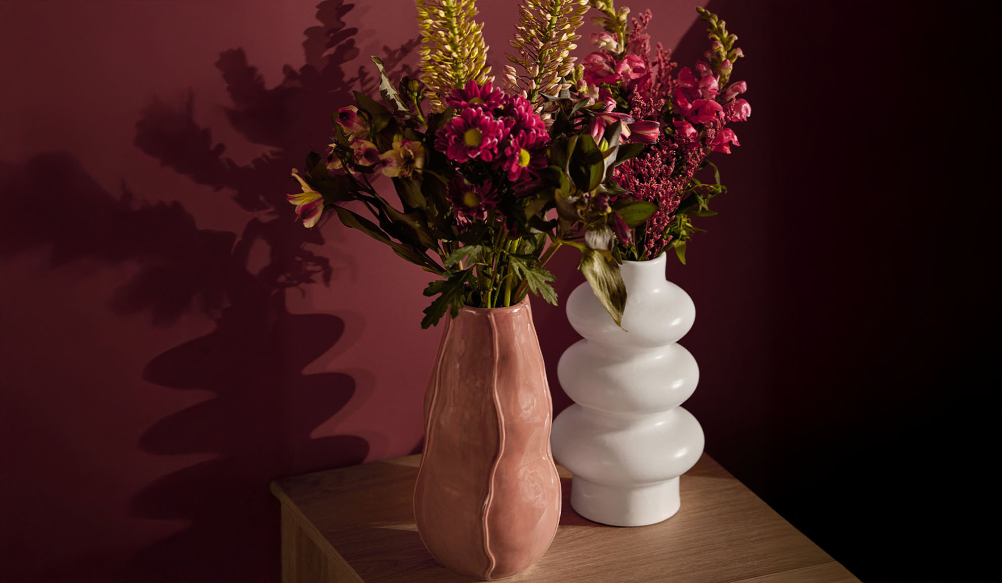 Deux vases avec des fleurs colorées sur une table en bois.