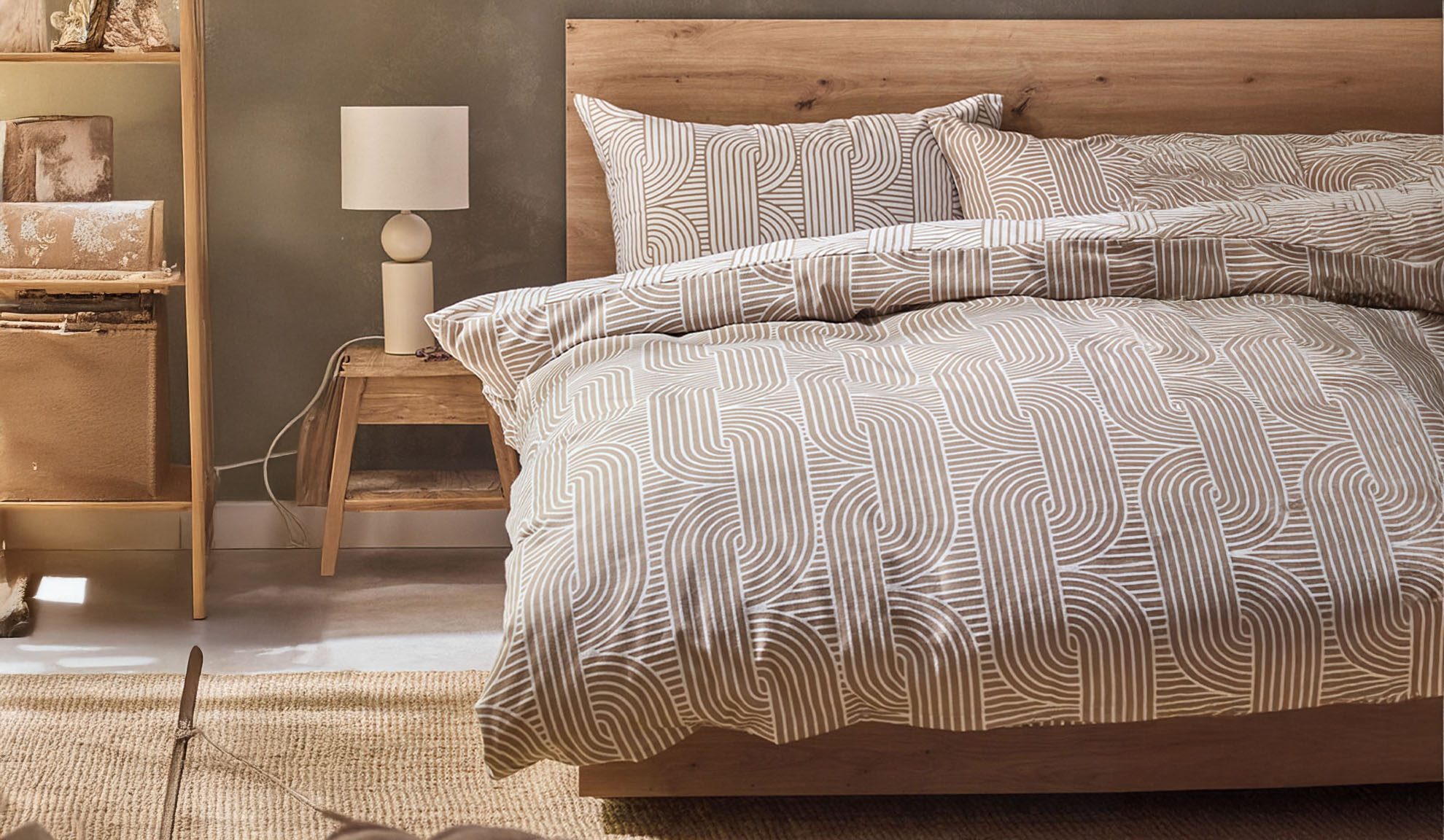 Chambre avec lit en bois, literie à motif géométrique et table de chevet avec lampe.