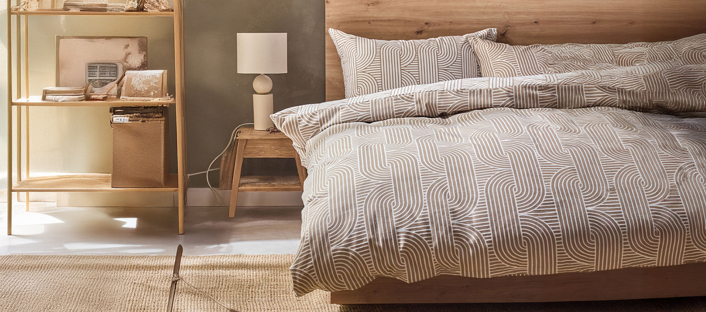Chambre avec lit en bois, housse de couette à motifs, table de chevet et étagère.