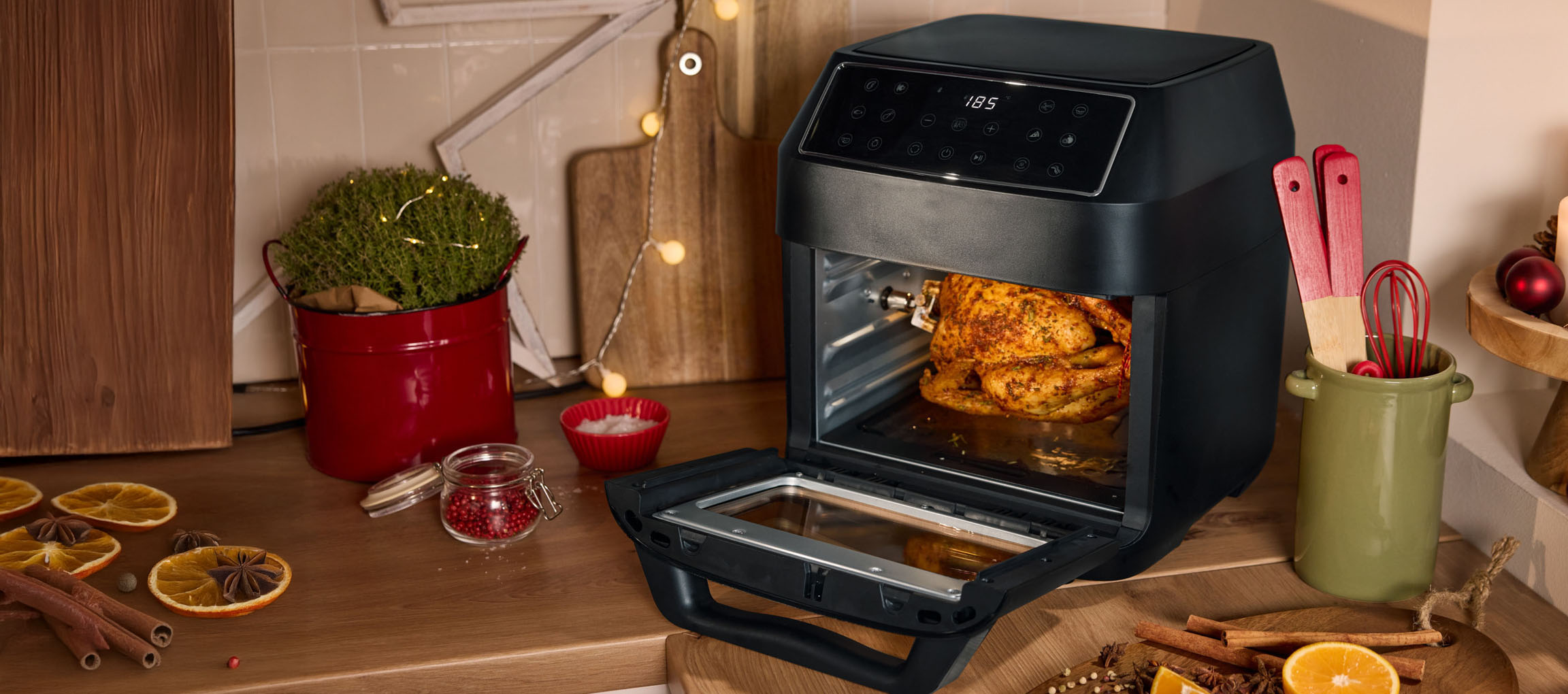 Friteuse à air chaud avec poulet rôti dans une cuisine décorée pour Noël.