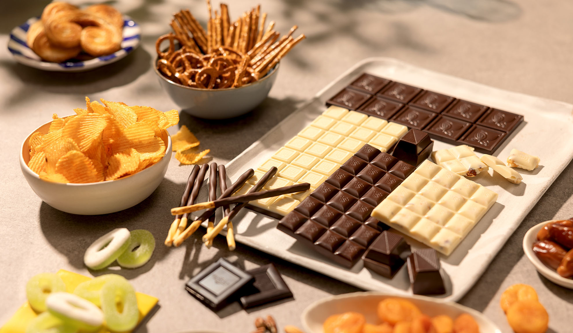 Un assortiment de snacks comprenant des barres de chocolat, des chips, des bretzels et des bonbons.