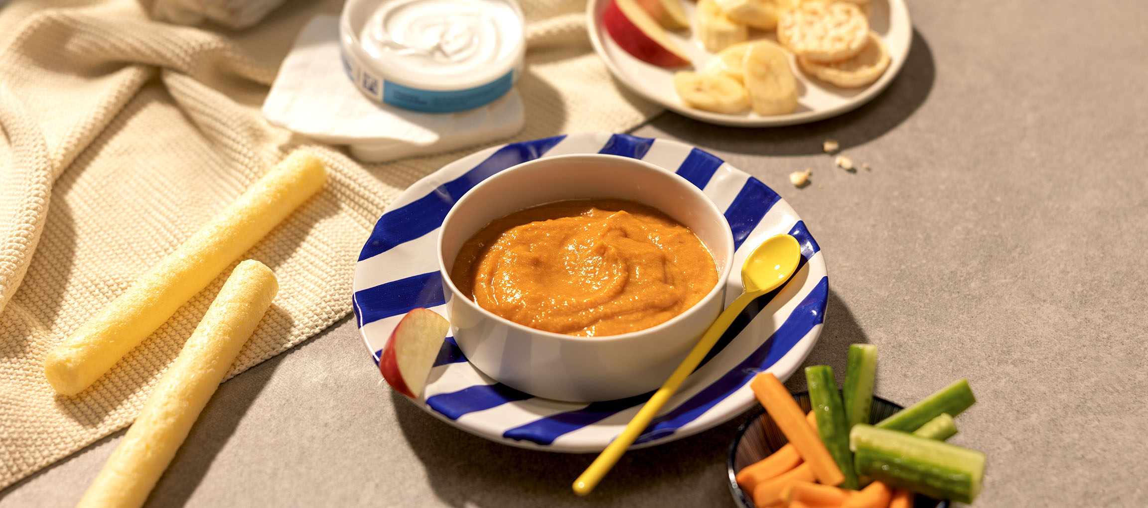 Purée pour bébé avec des collations comme des fruits, des crackers et des bâtonnets de légumes.