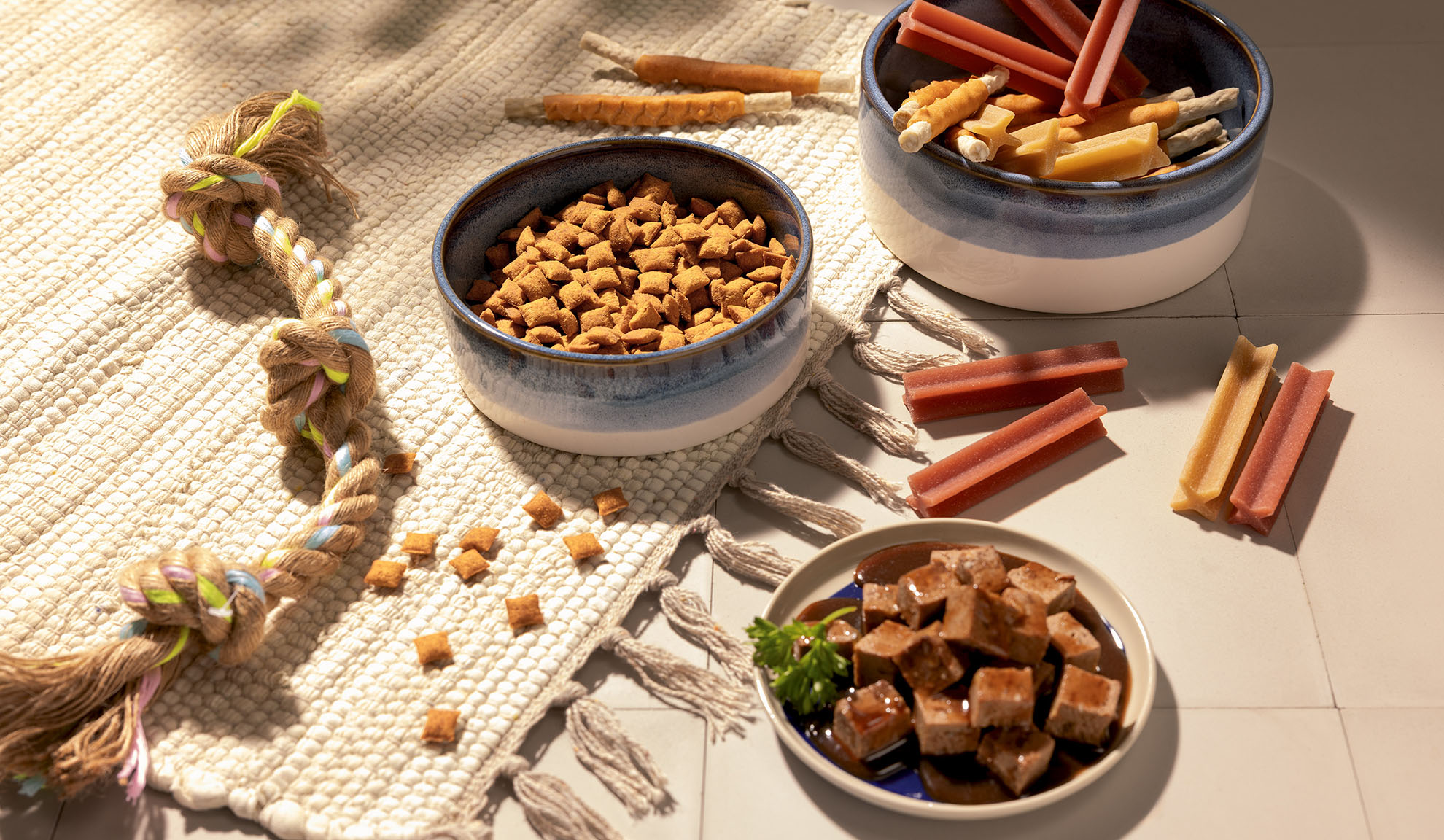 Assortiment de nourriture et friandises pour animaux, incluant croquettes, pâtée et bâtonnets à mâcher.