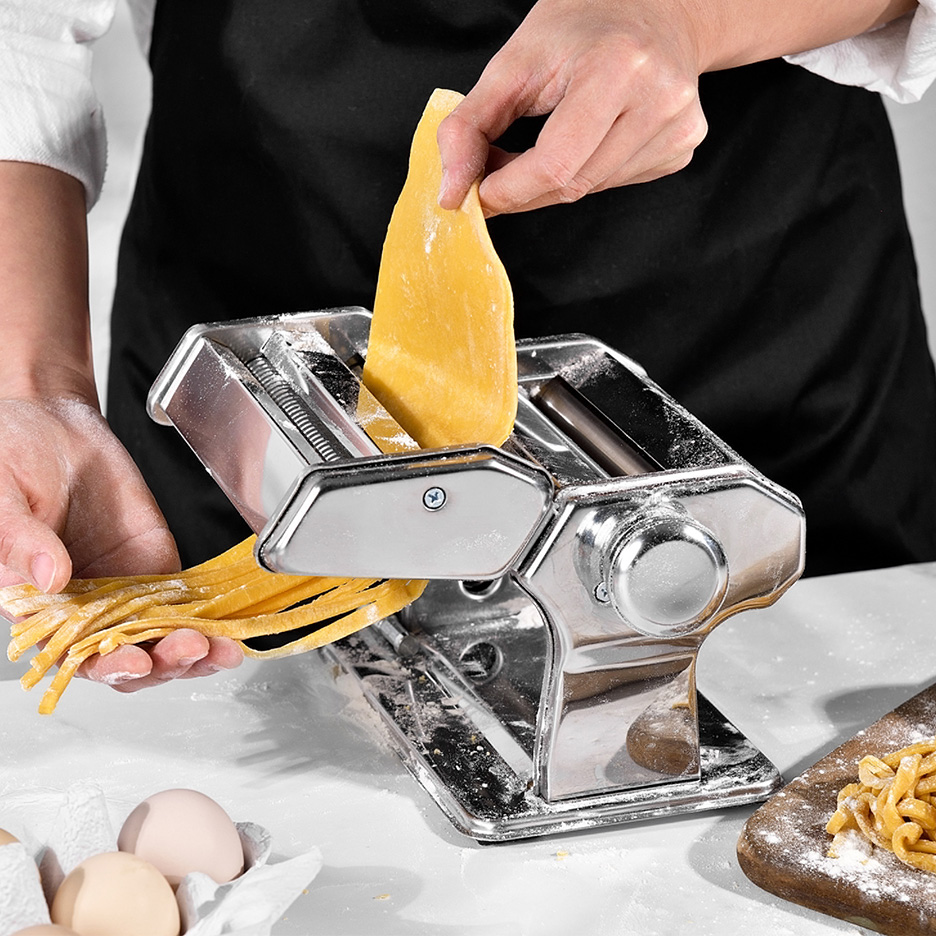 Une personne utilise une machine à pâtes pour faire des nouilles fraîches.