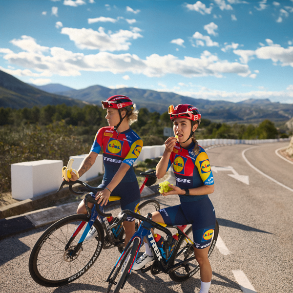 Deux cyclistes de l'équipe Trek-Segafredo Lidl profitent d'une pause avec des fruits.