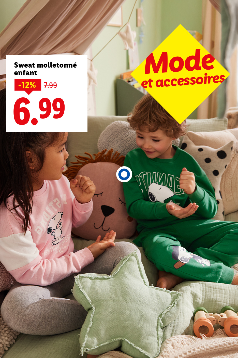 Deux enfants portant des sweats Snoopy, l'un rose et l'autre vert, avec des coussins.
