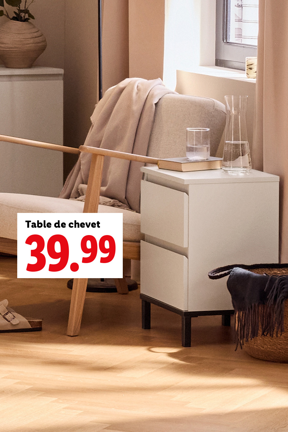 Une table de chevet blanche avec deux tiroirs, affichée à 39,99, à côté d'un fauteuil et d'une fenêtre.