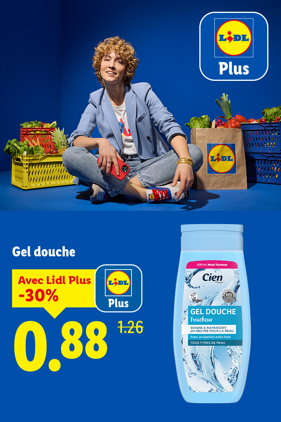 Une femme souriante assise au milieu de courses, avec une bouteille de gel douche en promotion.