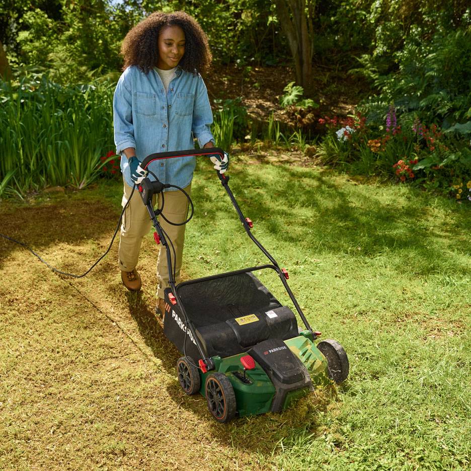 Femme utilisant un scarificateur électrique dans le jardin.
