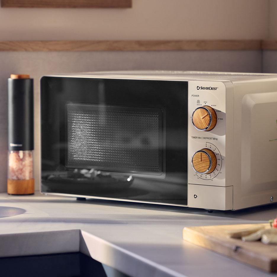 Micro-ondes crème avec boutons en bois sur un comptoir de cuisine.