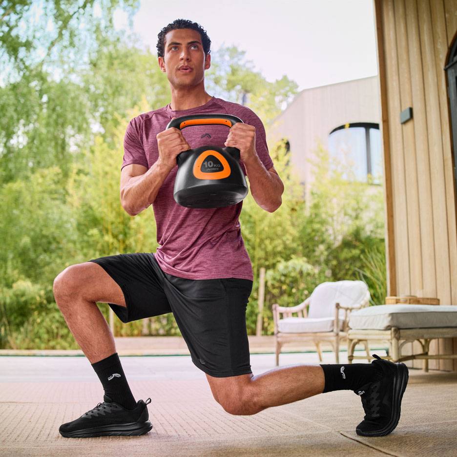 Homme faisant des fentes avec une kettlebell de 10 kg en extérieur.