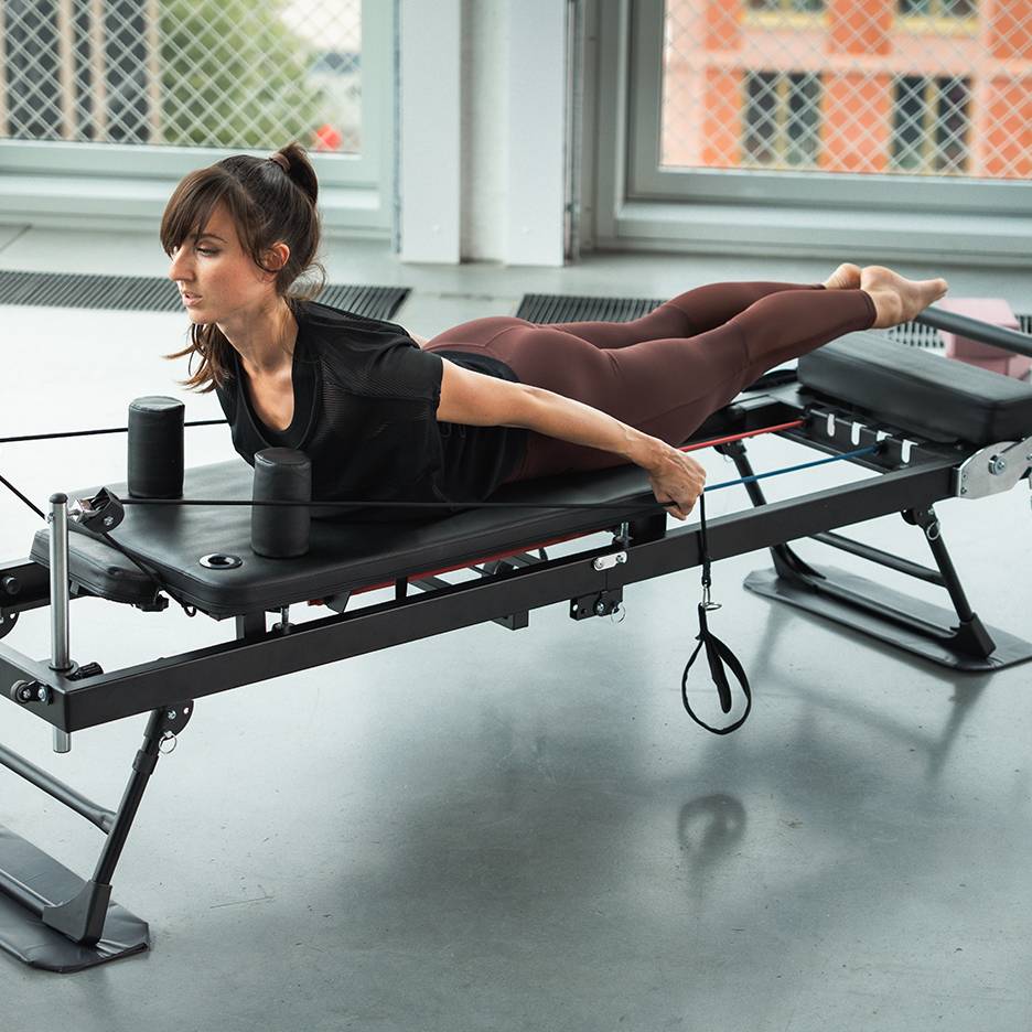 Femme faisant de l'exercice sur un appareil de Pilates avec des bandes de résistance.