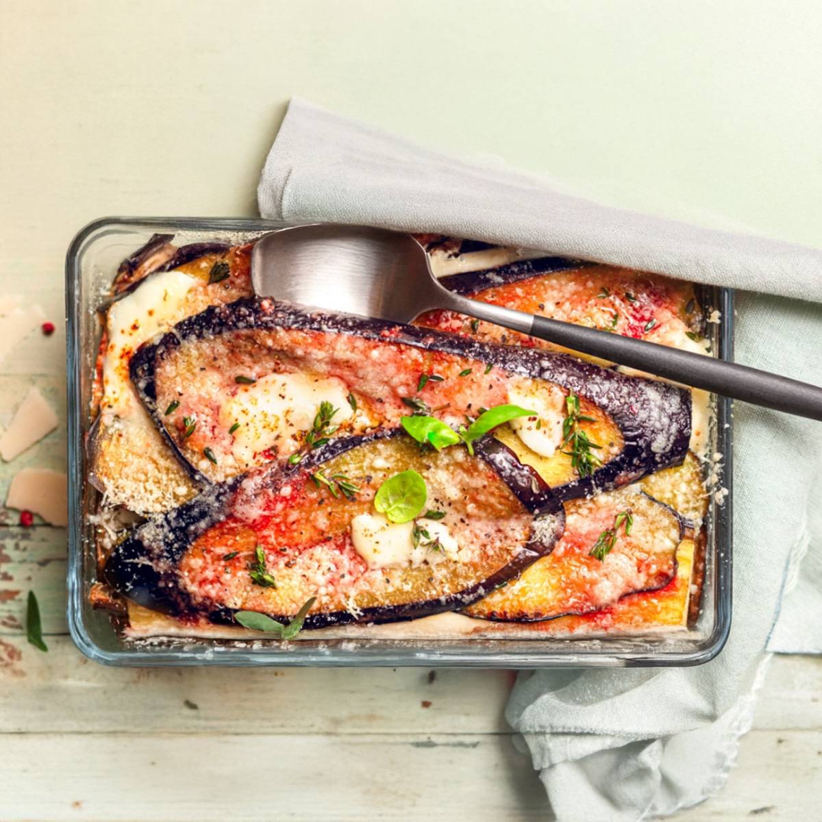 Gratin d'aubergines au fromage, servi dans un plat en verre.